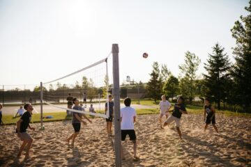 men playing volleyball near pine trees